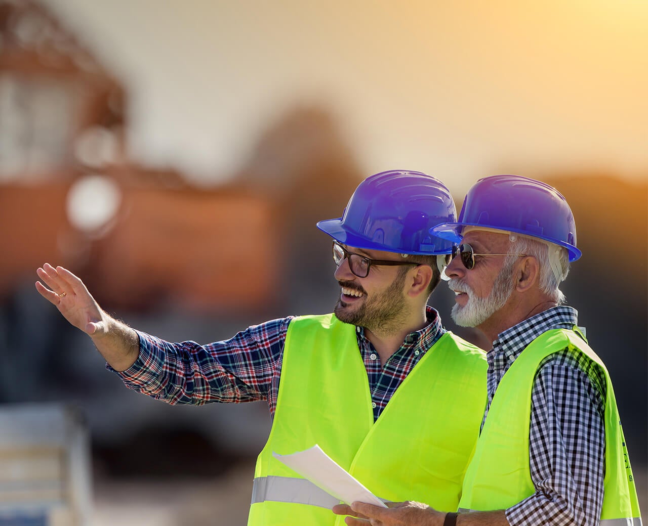Two Allan Myers employees on a construction site wearing hard hats and safety vests.