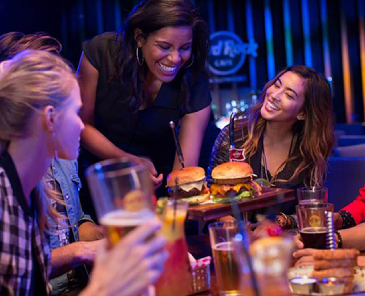 A waitress serving burgers to a table at a Hard Rock hotel & casino restaurant