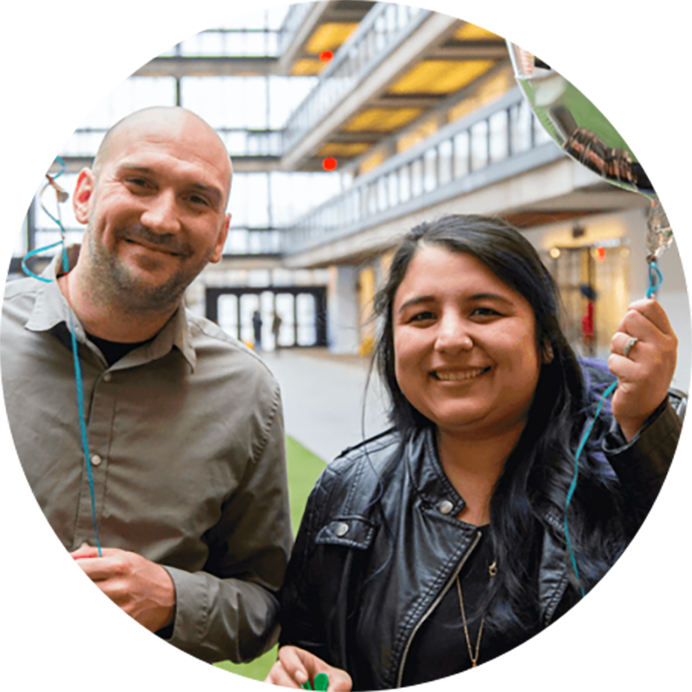 2 iCIMS employees smiling and holding balloons