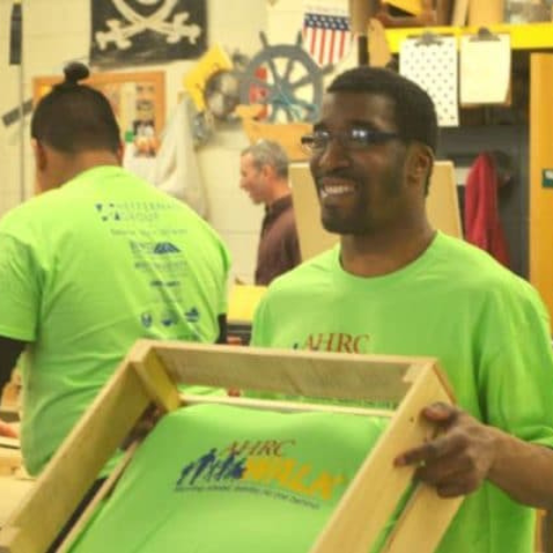 AHRC volunteer holds a box of shirts
